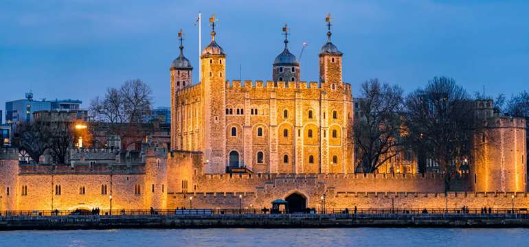 Večerne osvetlená pevnosť Tower of London nad Temžou