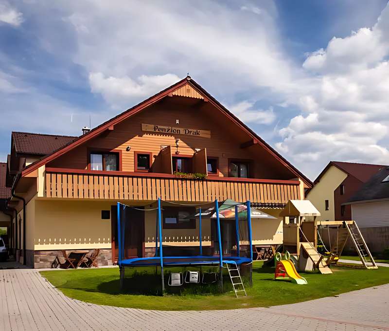 Drevený balkón penziónu Drak*** s trampolínou a preliezkami na trávniku, pre deti ako stvorené