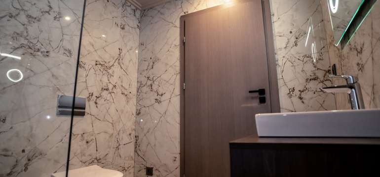 Kúpeľňa má elegantný dizajn so skleneným sprchovacím kútom, keramickými dlaždicami