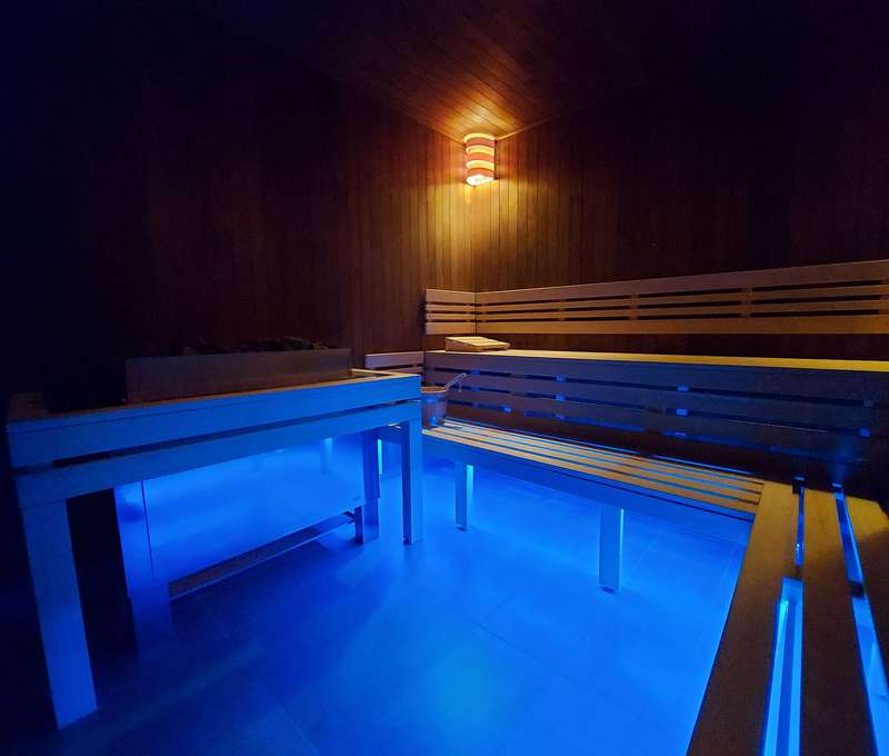 Fínska sauna dvojstupňová. Zdrojom tepla je elektrická pec s košom na lávové kamene.