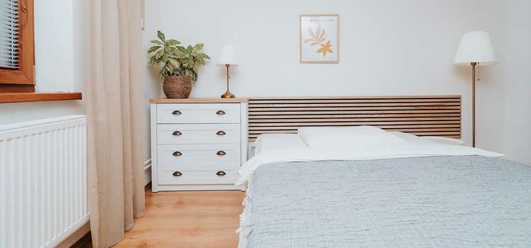 Svetlá spálňa apartmánu v depandance s manželskou posteľou a komodou
