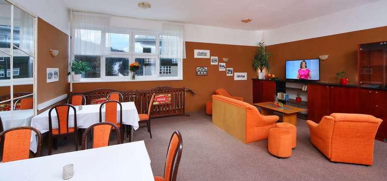K posezení slouží kromě hotelové restaurace i společenská místnost