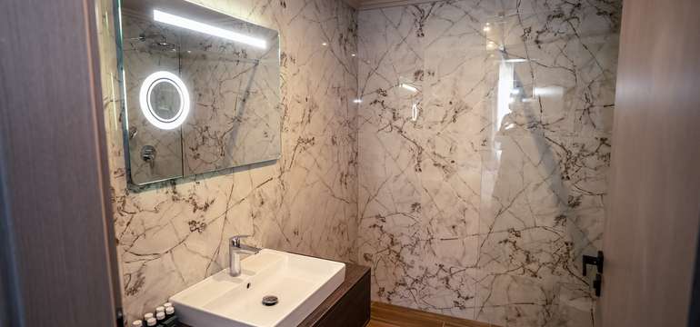 Kúpeľňa má elegantný dizajn so keramickými dlaždicami a vlastnými umývadlami a LED zrkadlom.