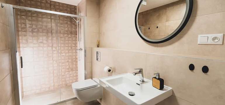 Kúpeľňa so sprchovacím kútom, umývadlom a toaletou v apartmáne