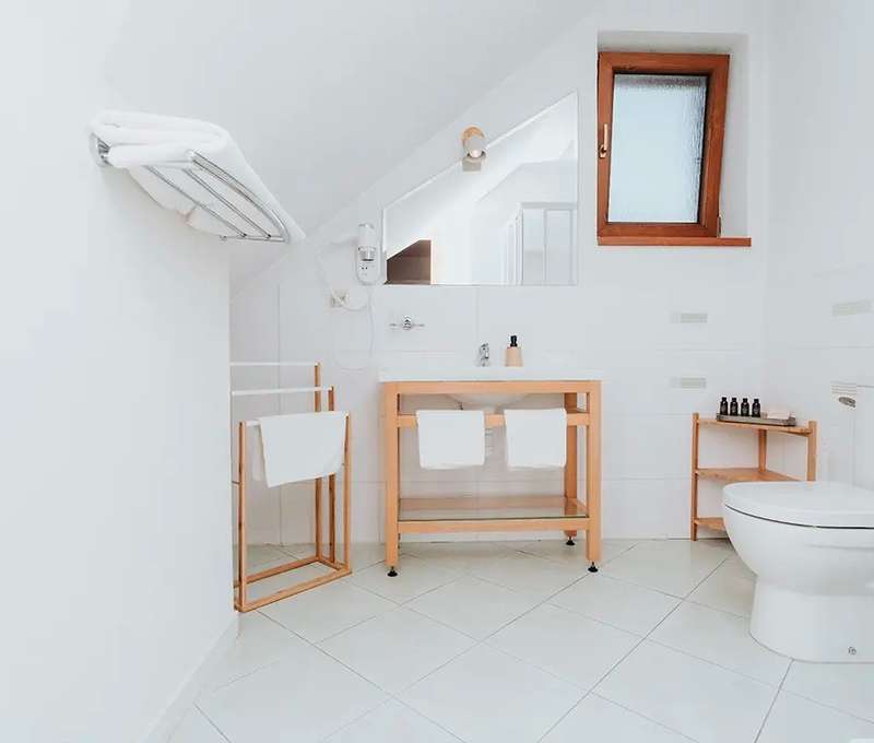 Biela kúpeľňa apartmánu v depandance s drevenými doplnkami