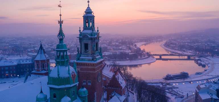 Zasnežený kráľovský hrad Wawel nad riekou Vislou pri západe slnka, Krakov