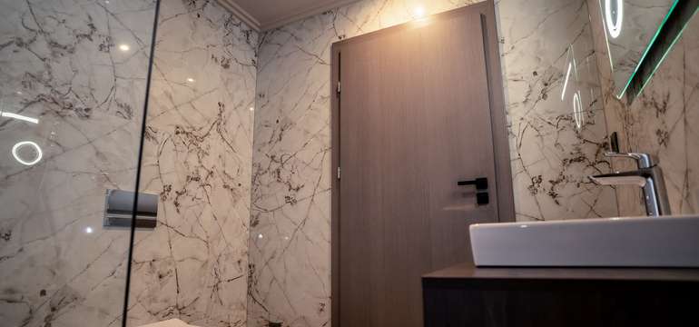 Kúpeľňa má elegantný dizajn so skleneným sprchovacím kútom, keramickými dlaždicami