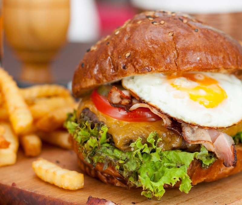 Chutný burger s hranolkami a cibuľovými krúžkami (ilustračný obrázok)