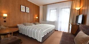 Každá dvojlôžková izba má manželskú posteľ, nočné stolíky, kreslo so stolíkom, TV, úložný priestor