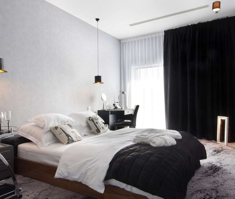 Černý apartmán nabízí odpočinek na velké dřevěné posteli s koženým čalouněním